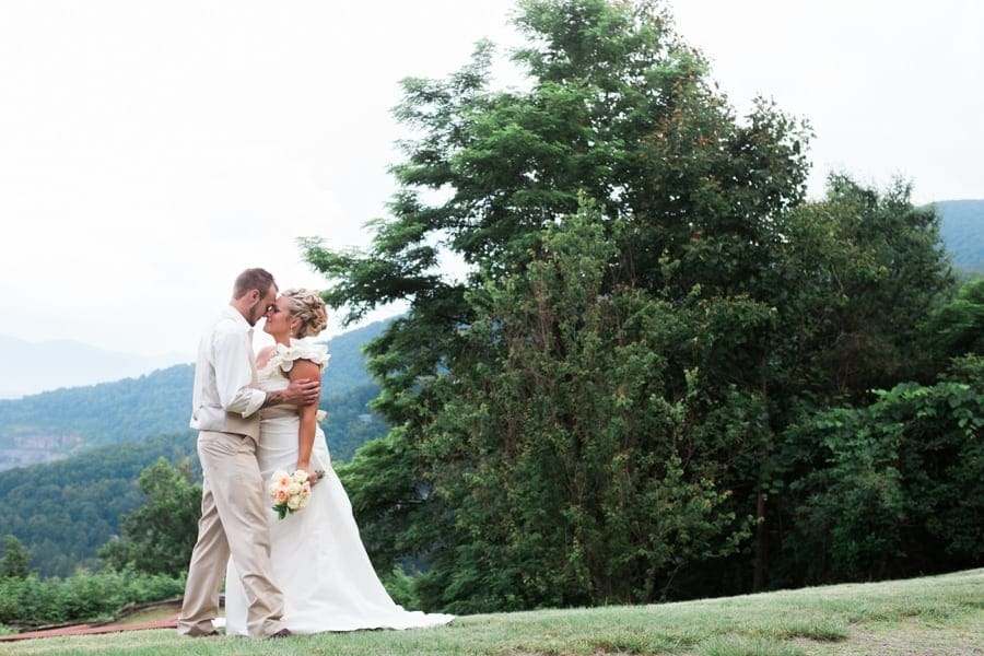 Bride and groom kiss with mountain view behind them