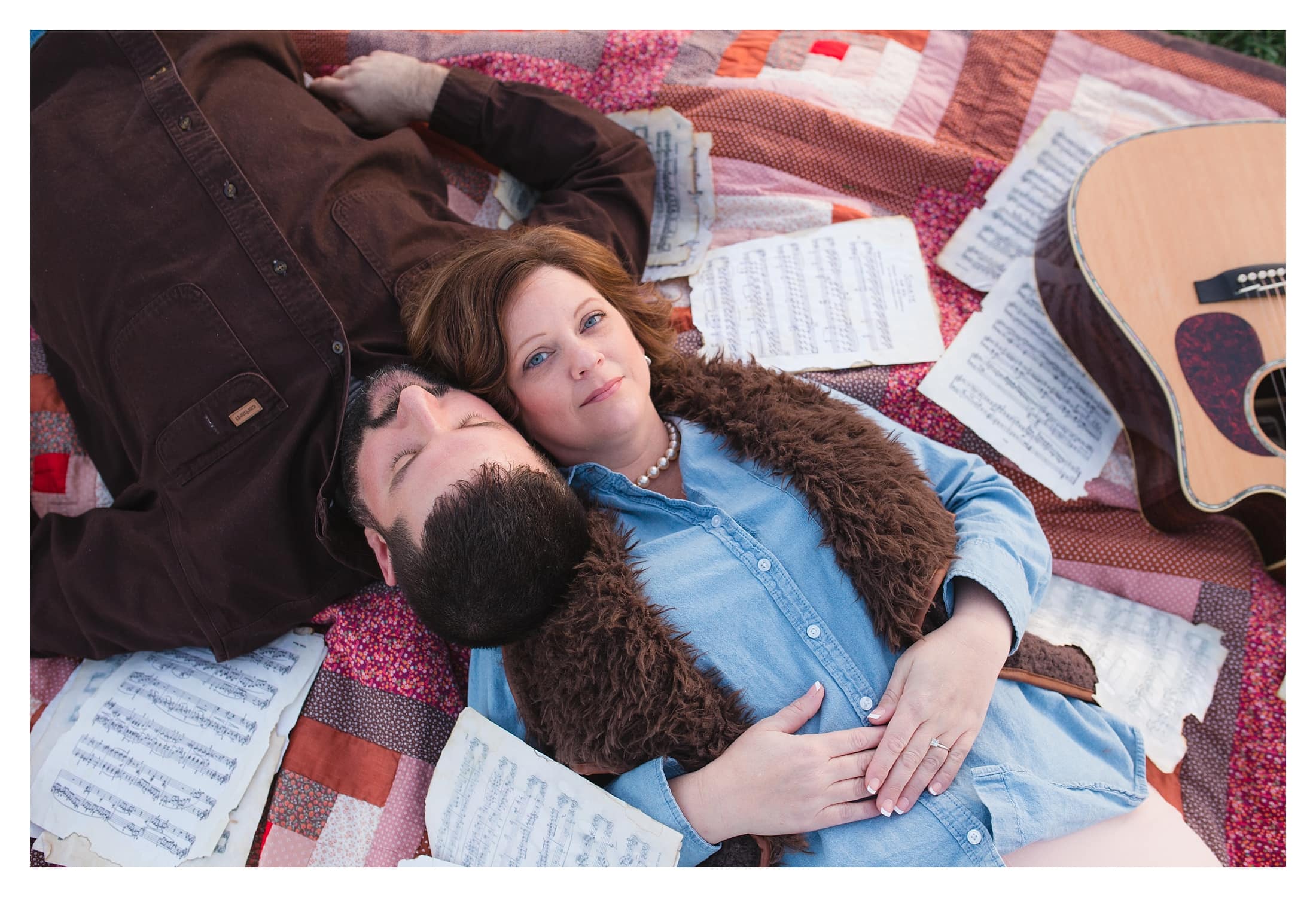 couple lying on quilt with a guitar and vintage sheet music scatter about.