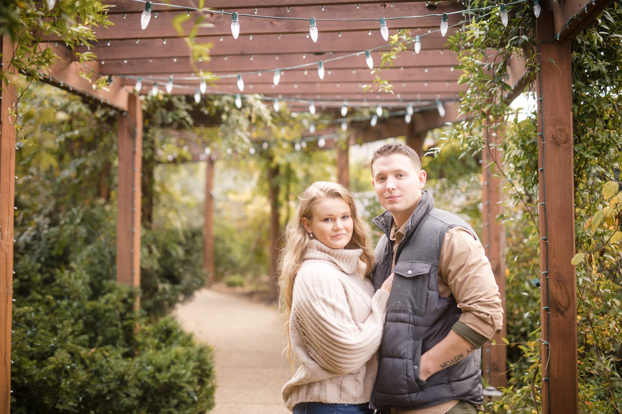 Couple posing affectionately for the camera under garden trellis at Biltmore Estate North Carolina photography done by Kathy Beaver.