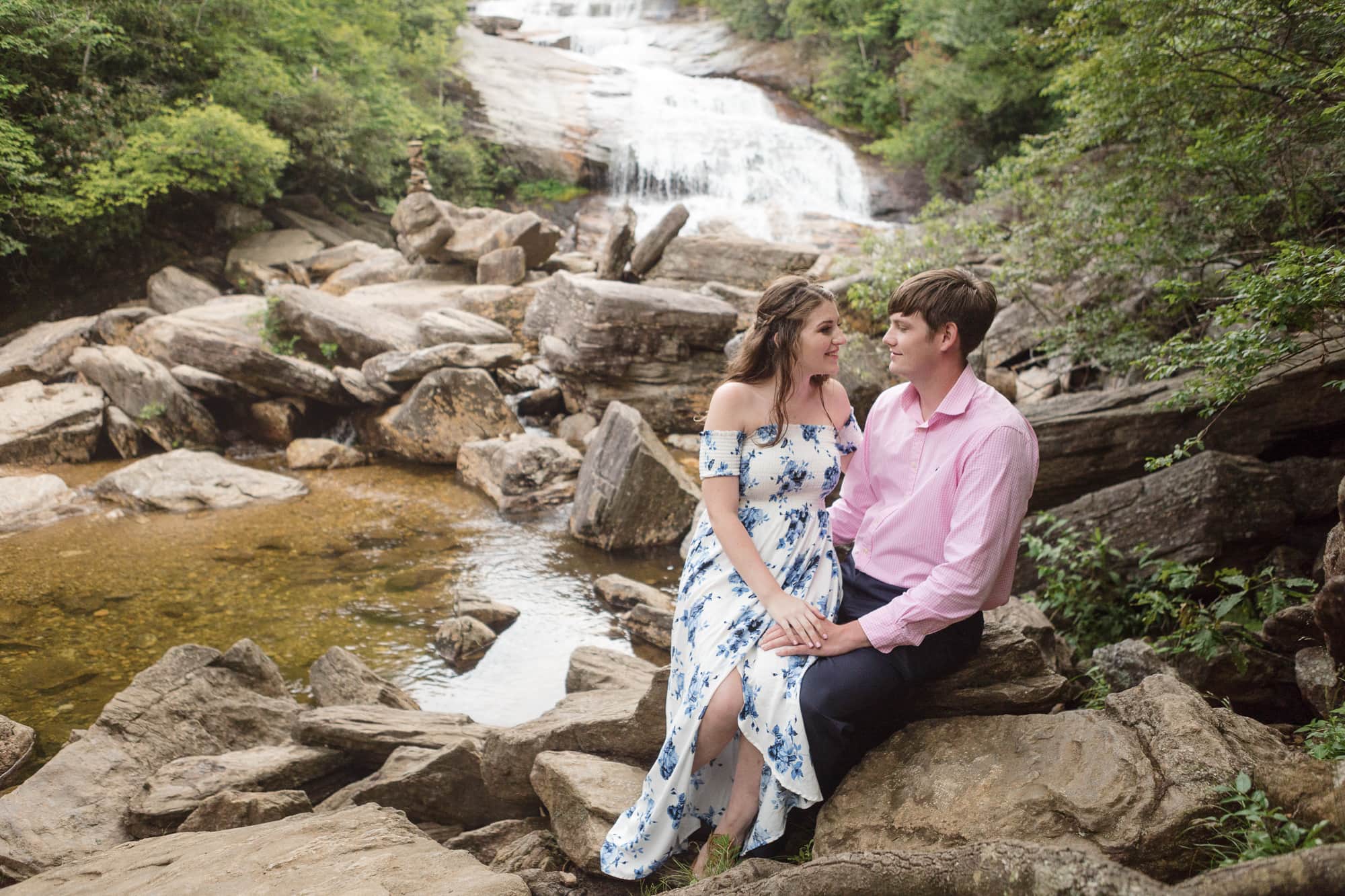 Couple sitting on rock near with waterfall behind them in Brevard North Carolina photography done by Kathy Beaver.