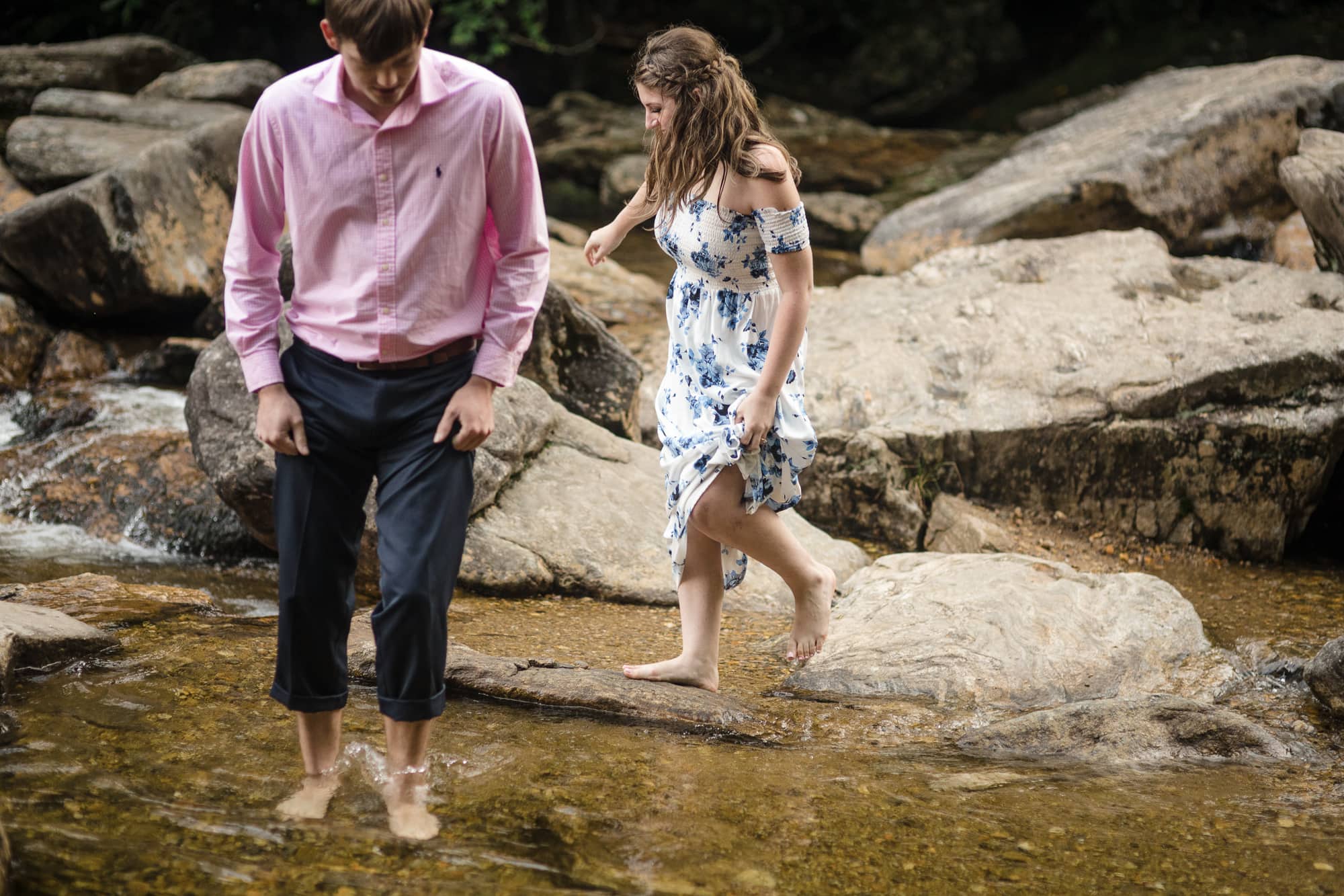 Couple walking barefoot across rocks in river near Brevard North Carolina photography done by Kathy Beaver.