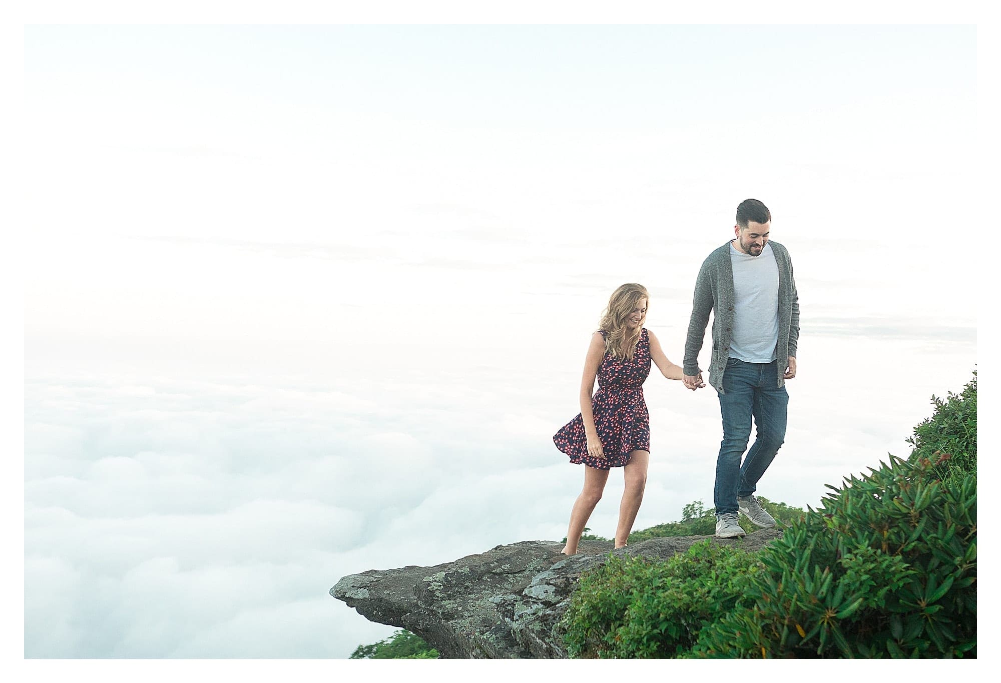 Engaged couple holding hands while walking on mountains edge