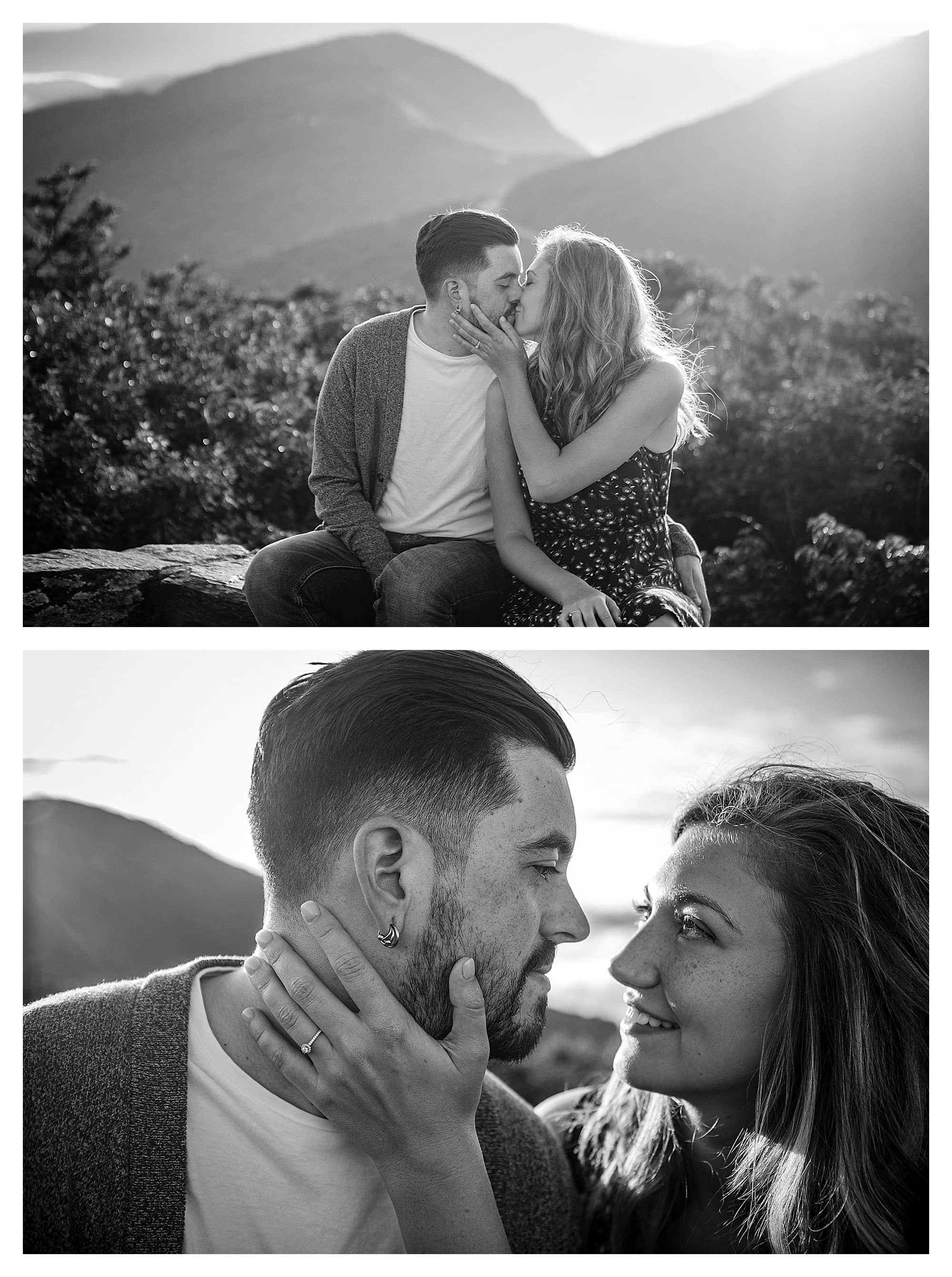 Black and white phots of engaged couple kissing while sitting on brick wall with mountains in background