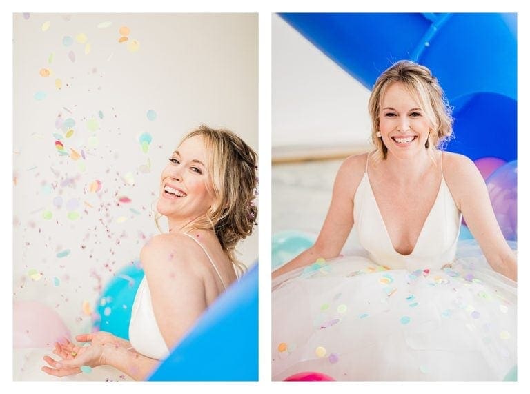 Bride in wedding dress laughing surrounded by many multi colored balloons