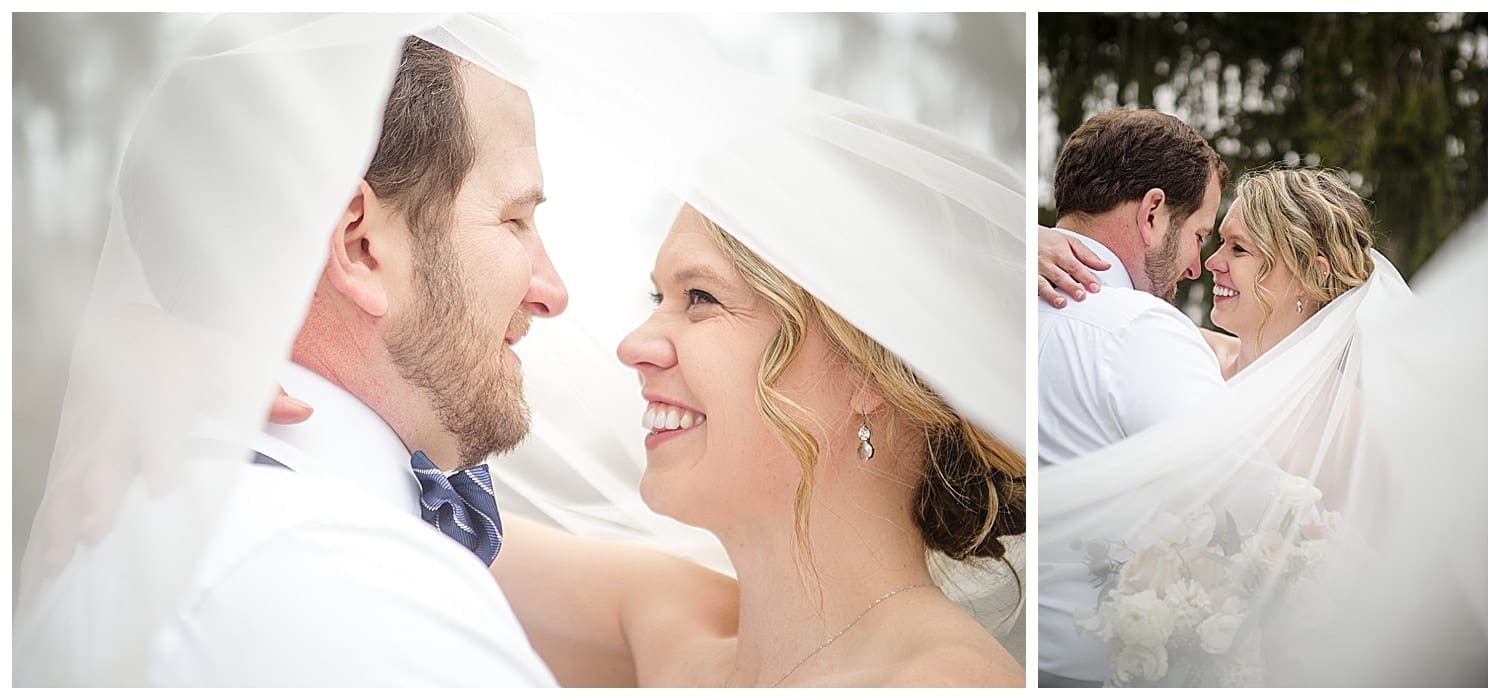 Bride and groom standing outside with treed background, arms around one another smiling