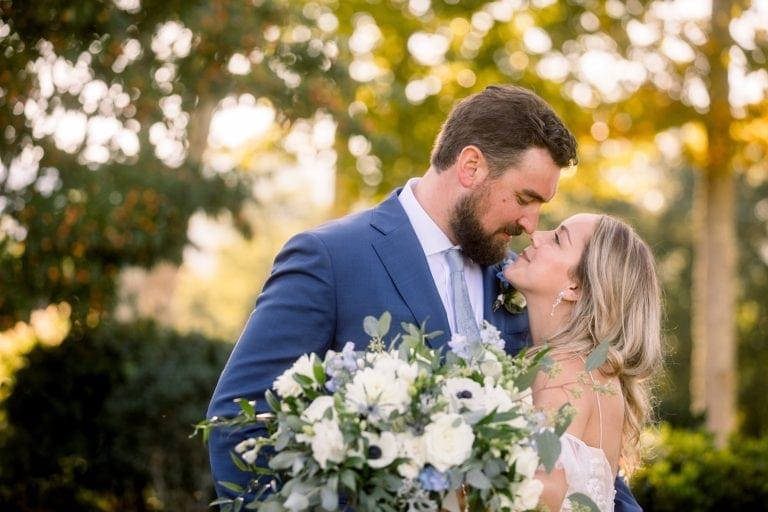 bride and groom with arms around one another's waist looking at each other smiling about to kiss