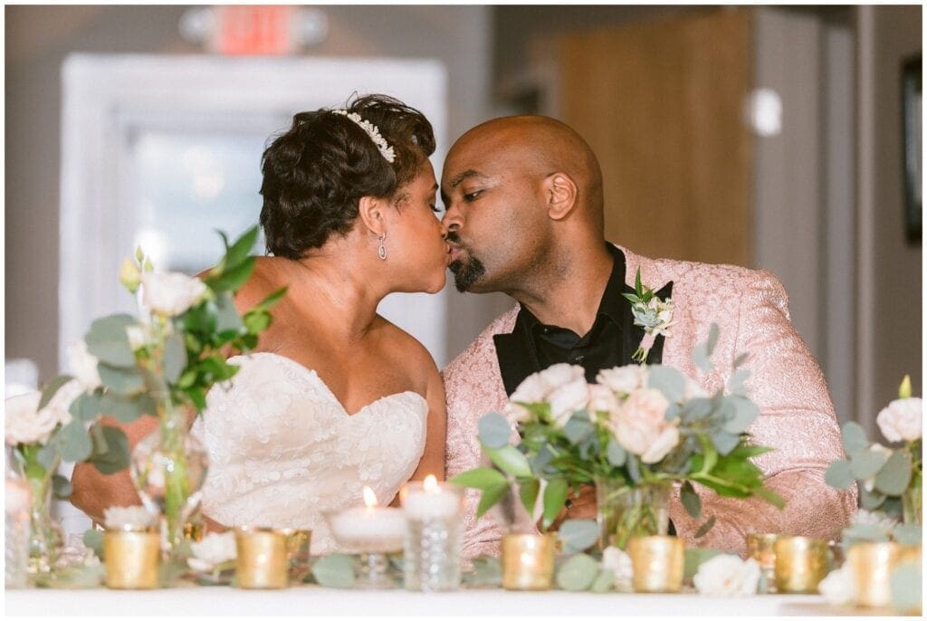 The bride and groom share a kiss at their table during their intimate dinner party wedding.