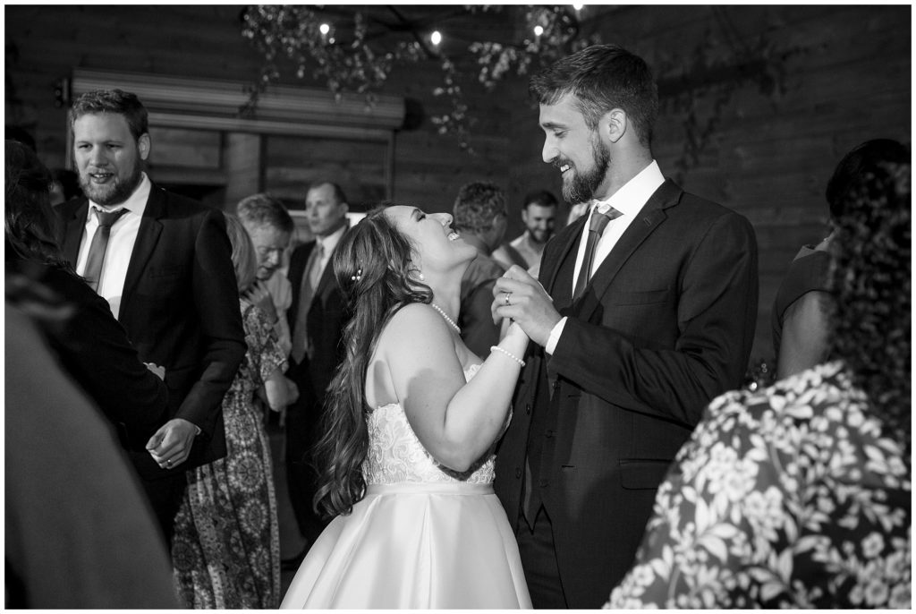 Black and white reception photo of the bride and groom dancing.