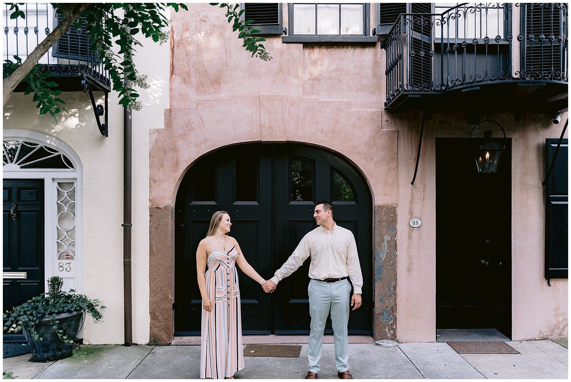 Couple standing in front of beautiful doors in Charleston, SC for their engagement portraits taken by Kathy Beaver Photography, a South Carolina wedding photographer.