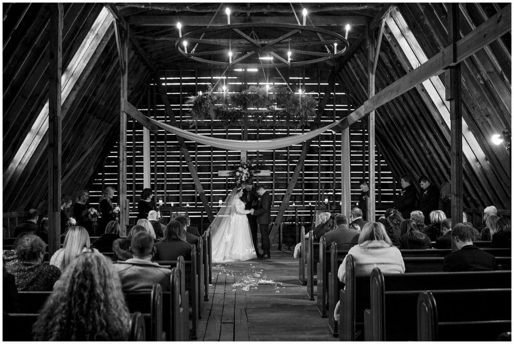 Rustic wedding ceremony in a barn with candles  | Asheville Wedding Photographer