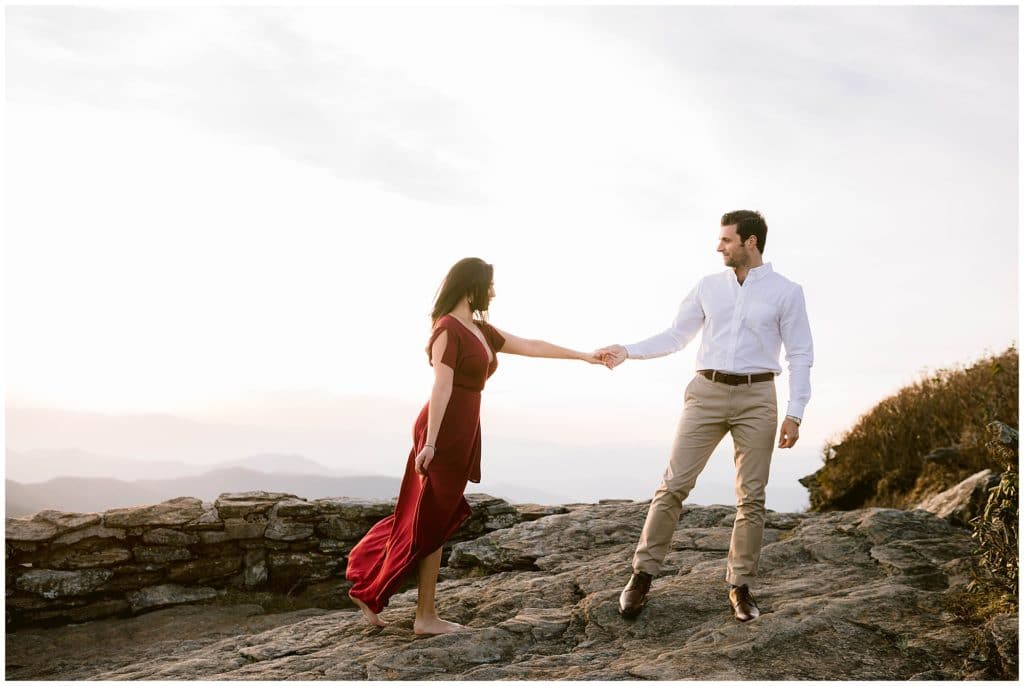 Steve holds Nicole's hand as they walk across the rocks at the Blue Ridge Parkway | Asheville Engagement Photographer