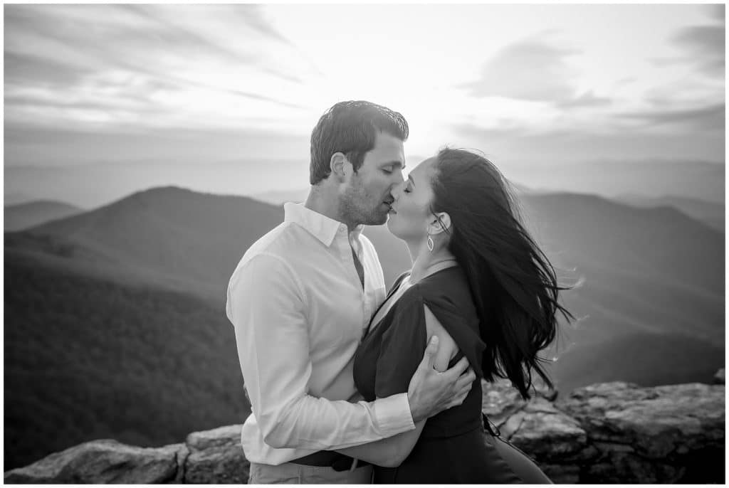 Black and white photo of Nicole and Steve sharing a kiss at sunset, with a view of the blue ridge parkway | Asheville Engagement Photographer