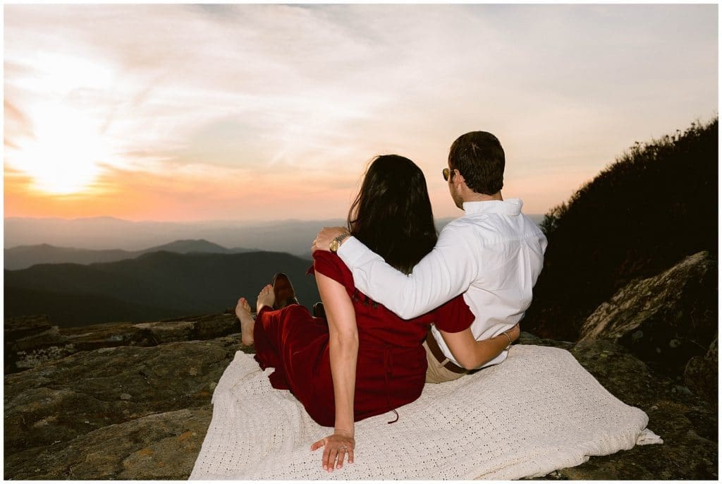 Nicole and Steve sit on a blanket together to watch the sunset | Asheville Engagement Photographer