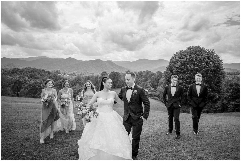 full wedding party photo in black and white, everyone walking and laughing