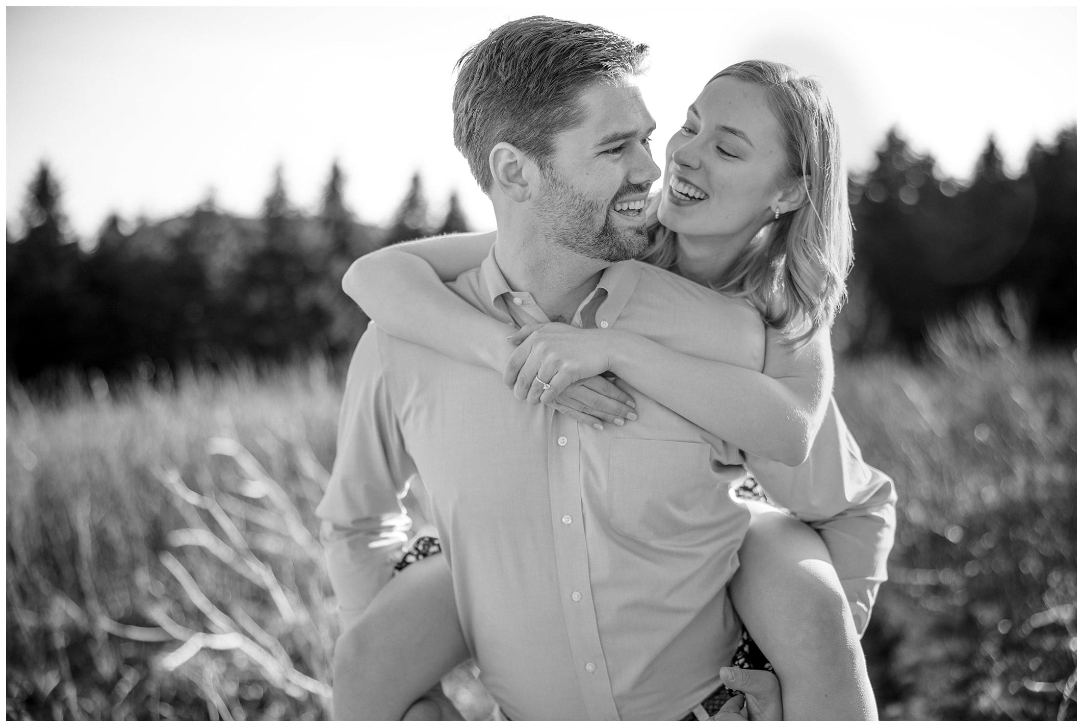 man gives woman piggy back as they pose for the engagement session in black and white
