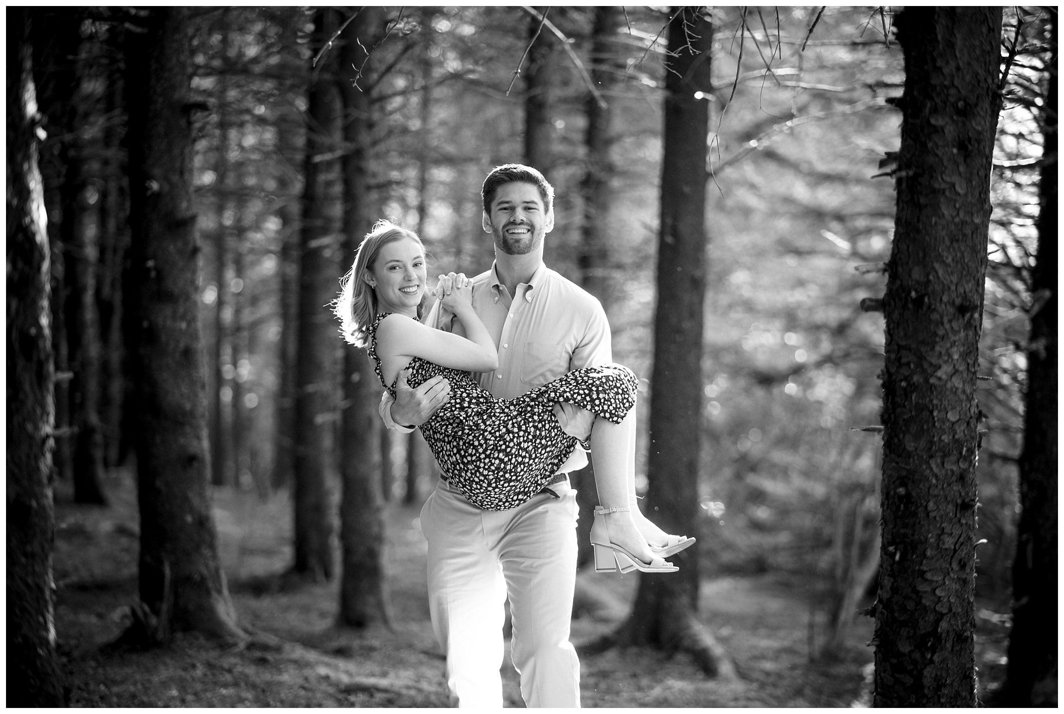 black and white photo of man holding woman for their engagement session in the woods