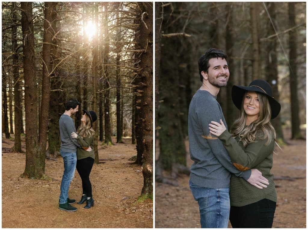 couple posing for their Asheville engagement session in the woods with the sun peeking through