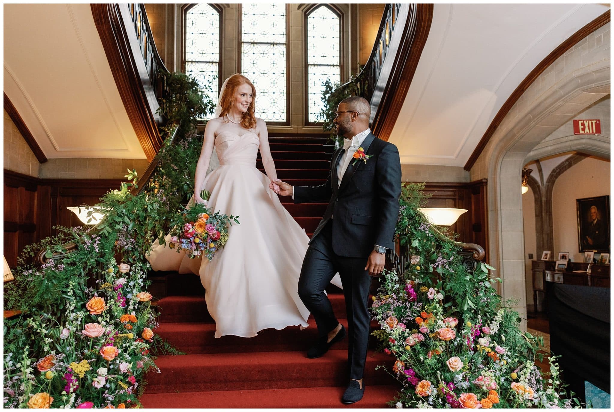 bride and groom walk down stairs with flower filled staircase for their Atlanta wedding