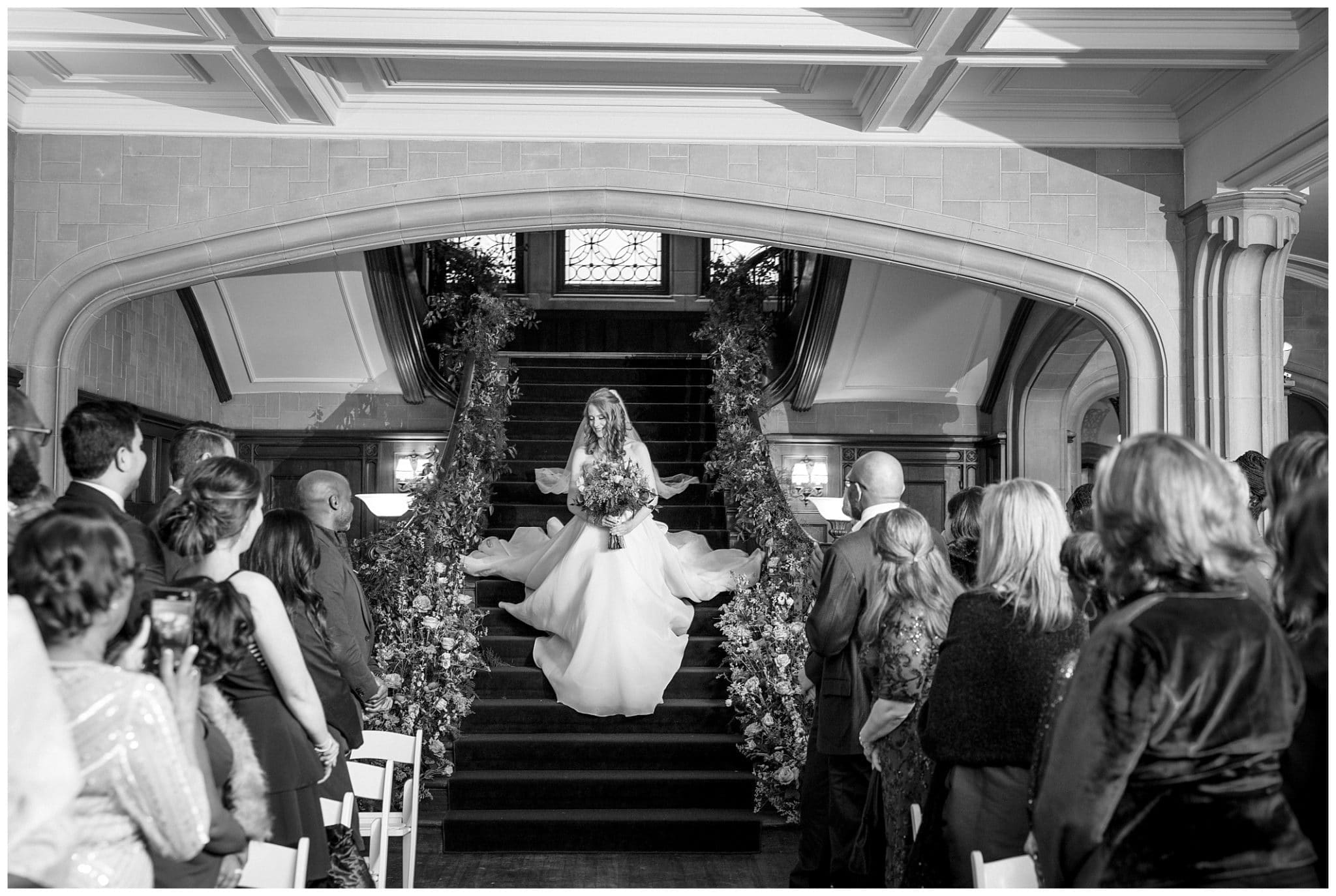 black and white photo of bride entering her ceremony down a staircase