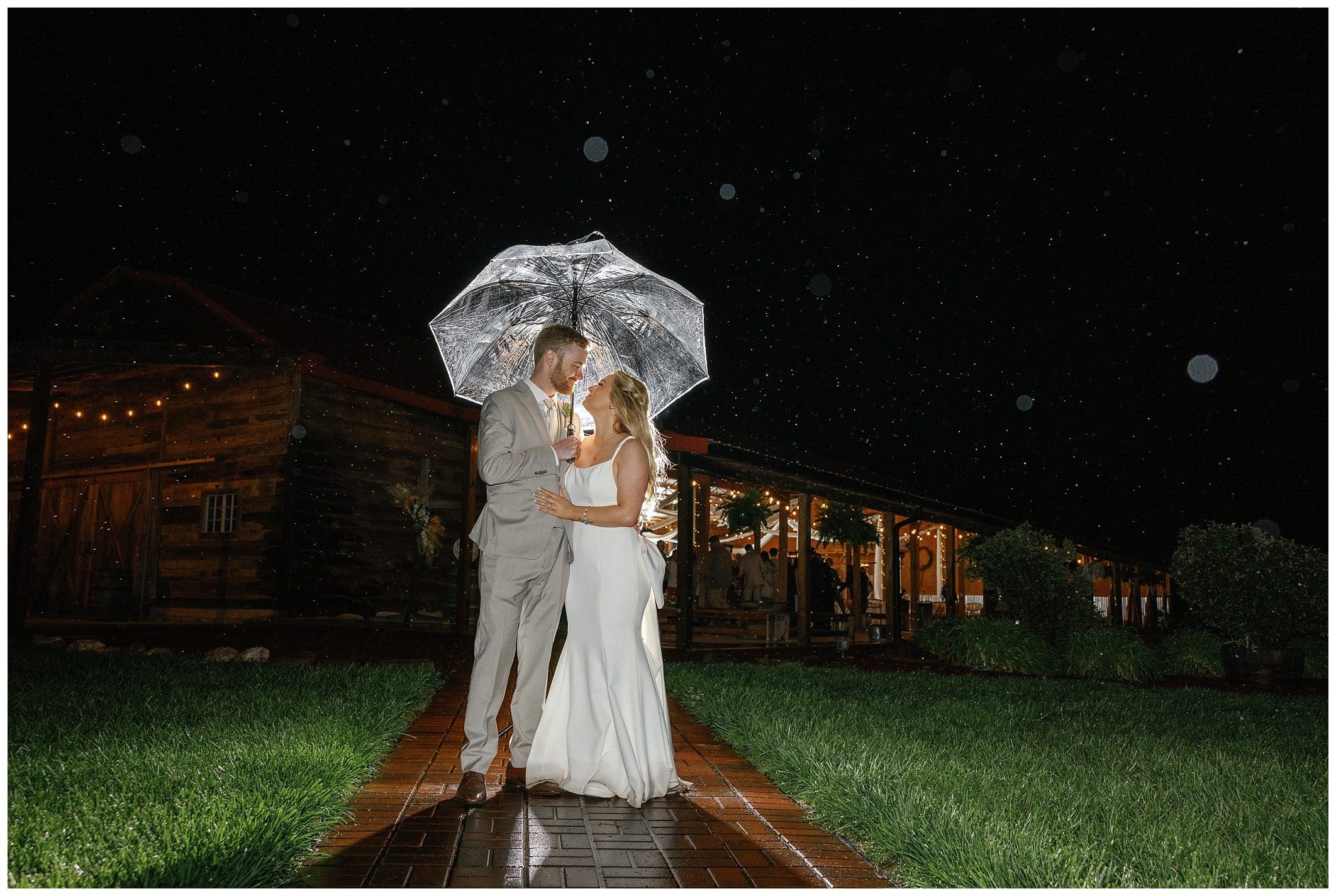 night photo of the bride and groom under. an umbrella at their rainy wedding day