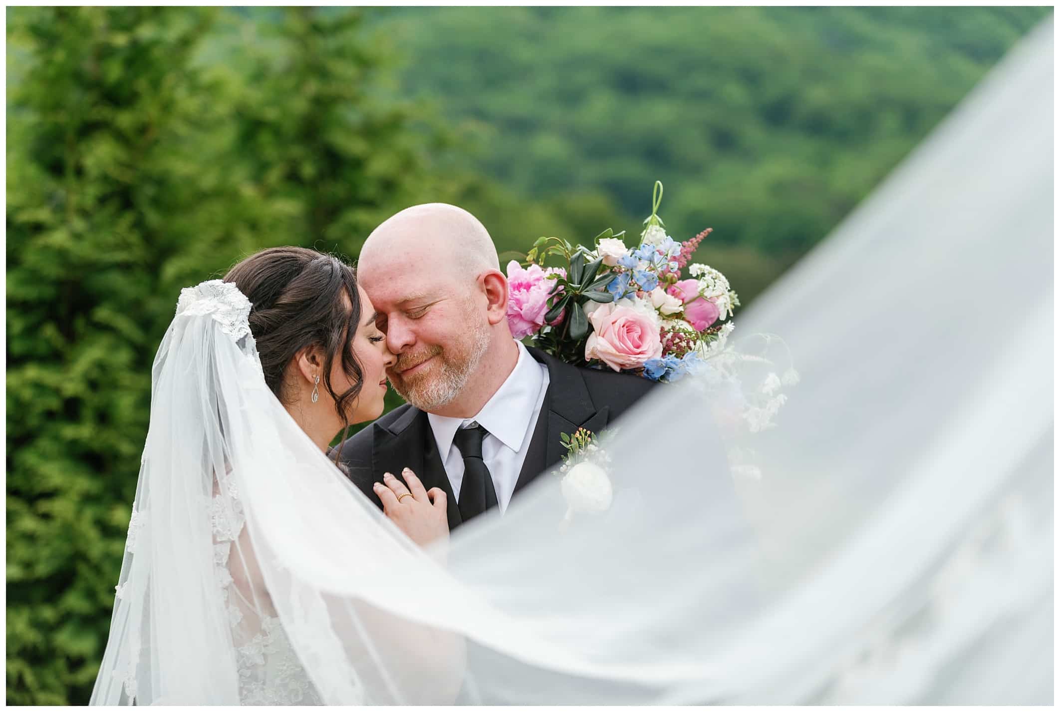 Bride and groom with veil wrapped around them