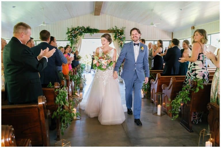 A bride and groom walking down the aisle of a church.