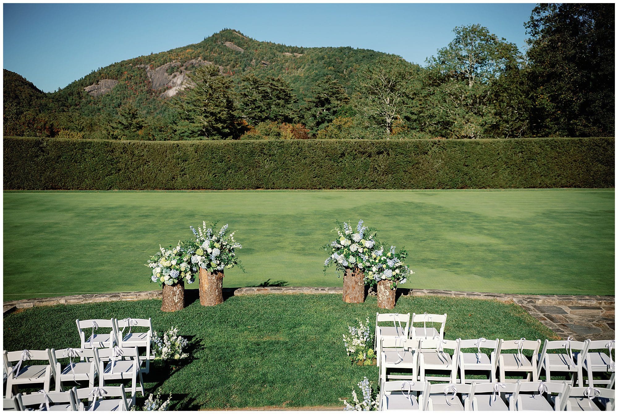 A wedding ceremony set up in a grassy area with mountains in the background.
