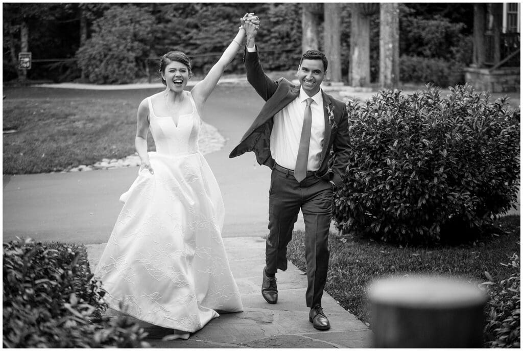 Black and white photo of bride and groom holding hands.