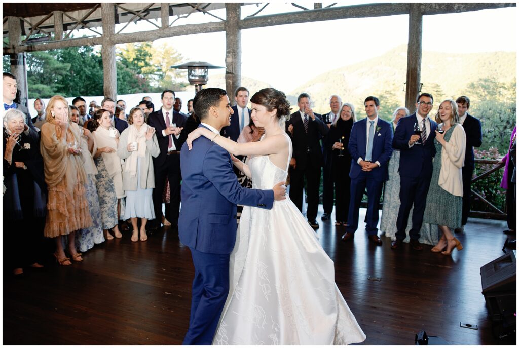 A bride and groom sharing their first dance in front of a crowd.