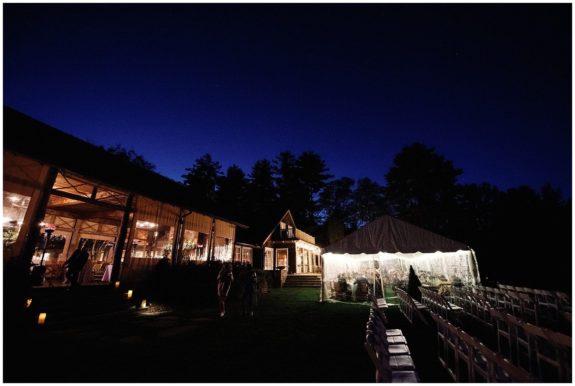 An outdoor wedding at night with a tent in the background.
