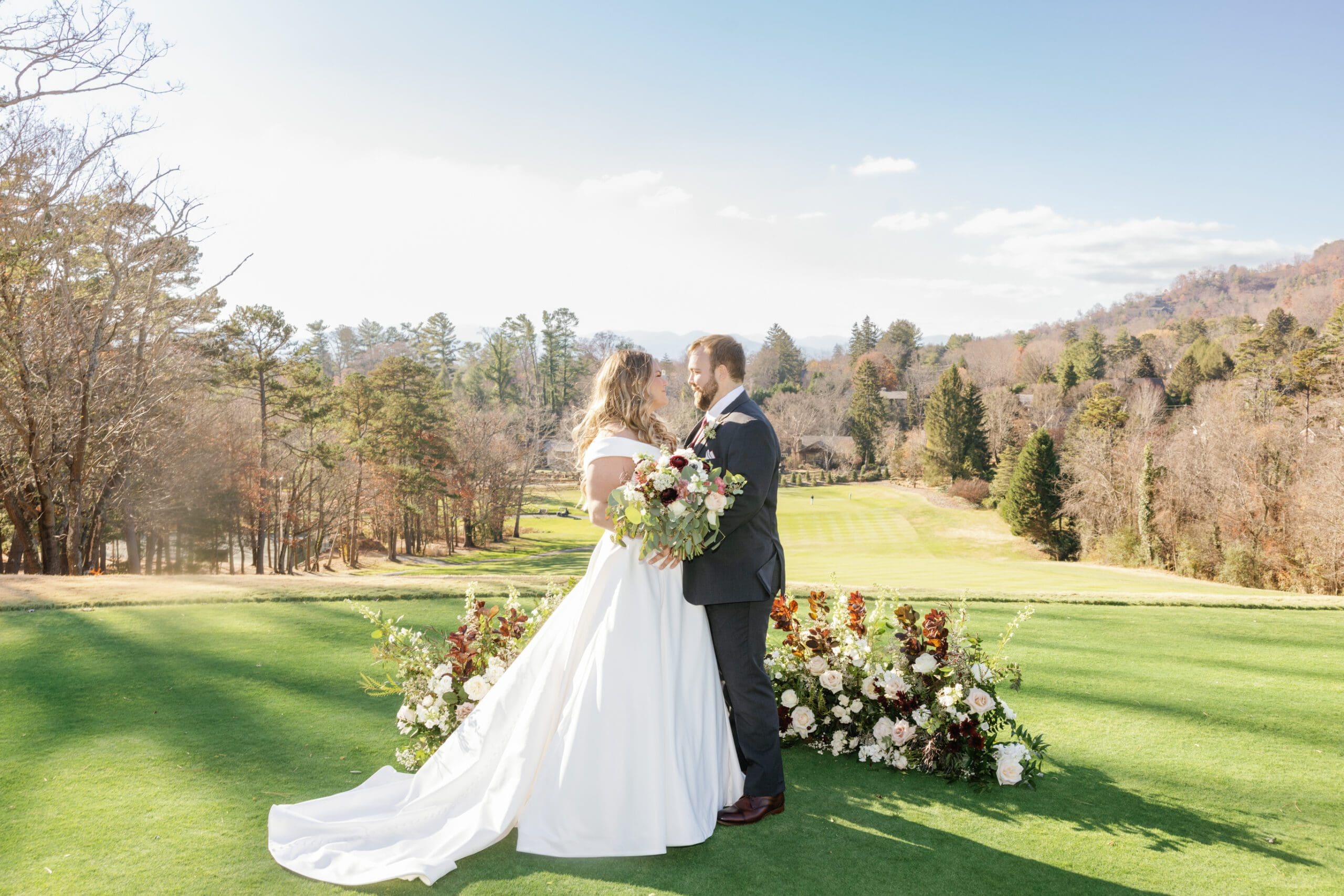 A fall wedding at the Country Club of Asheville, with a bride and groom kissing on the golf course.