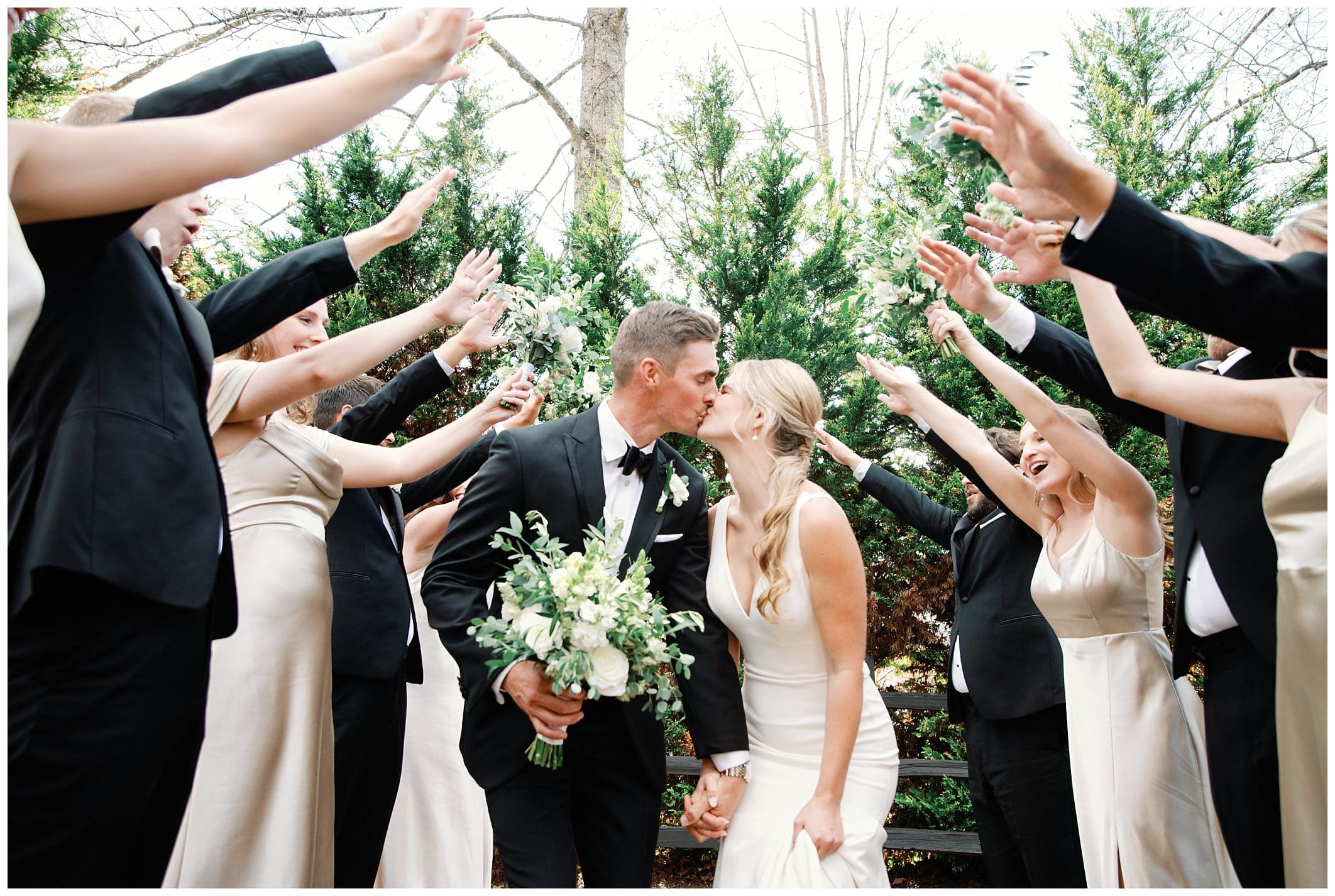 A fall wedding party at Crest Center joyously raises their hands in the air.
