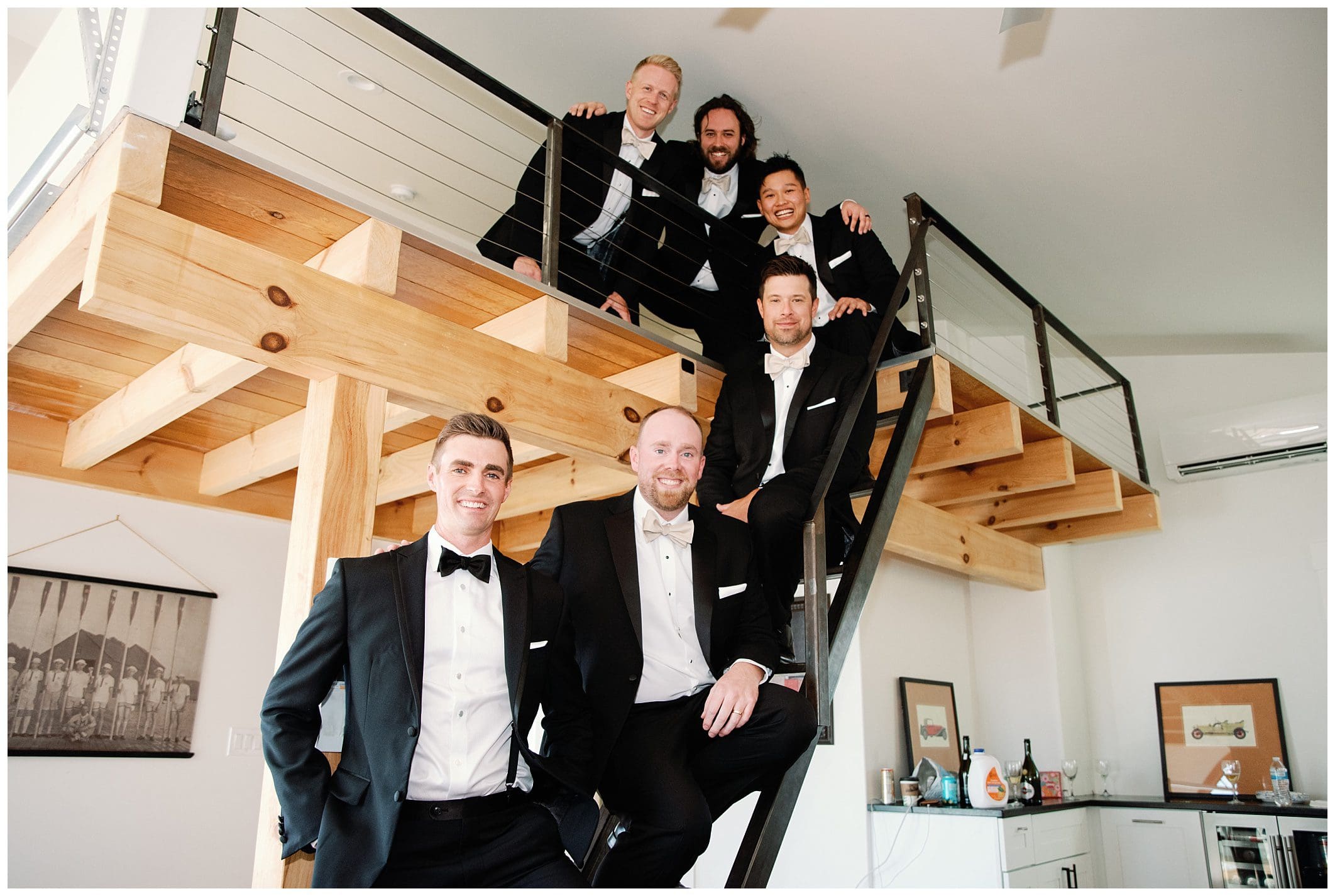 A group of men in tuxedos posing on a staircase at a fall wedding.