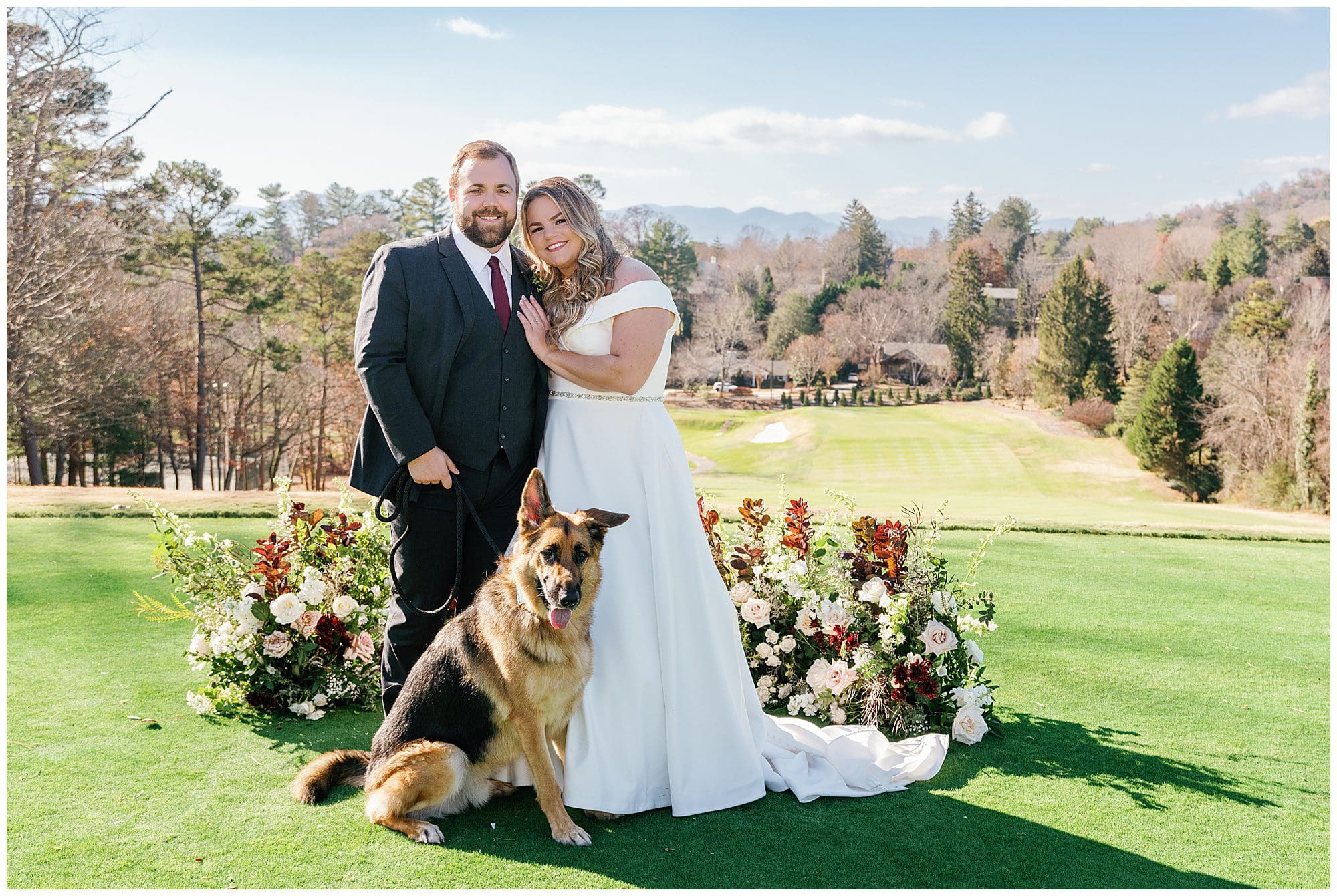 A bride and groom posing with their dog on the golf course.