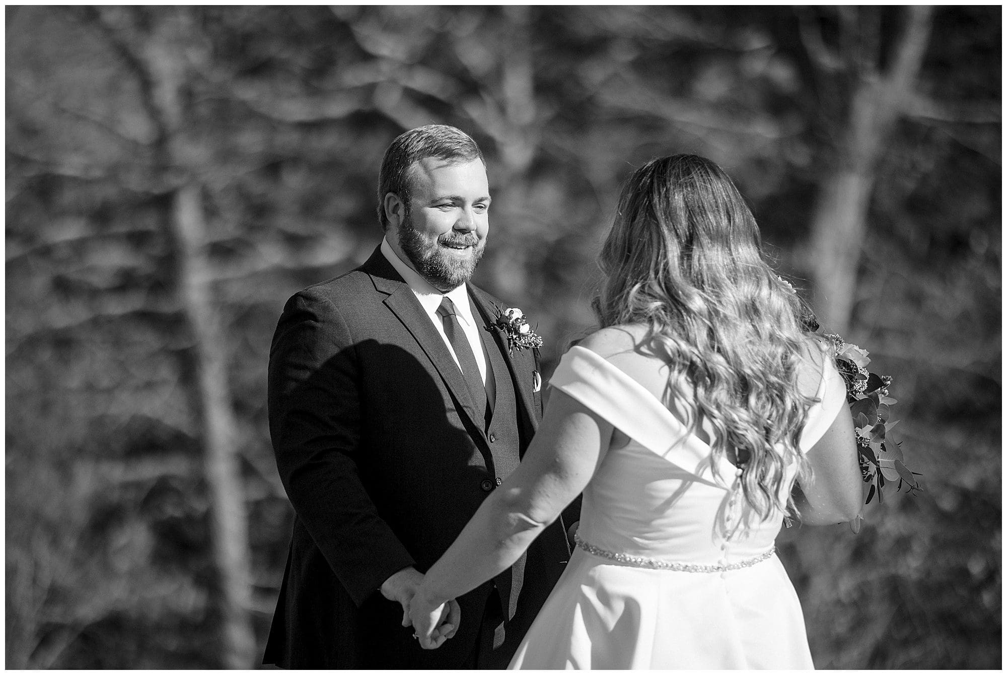 Black and white photo of a bride and groom in the woods.