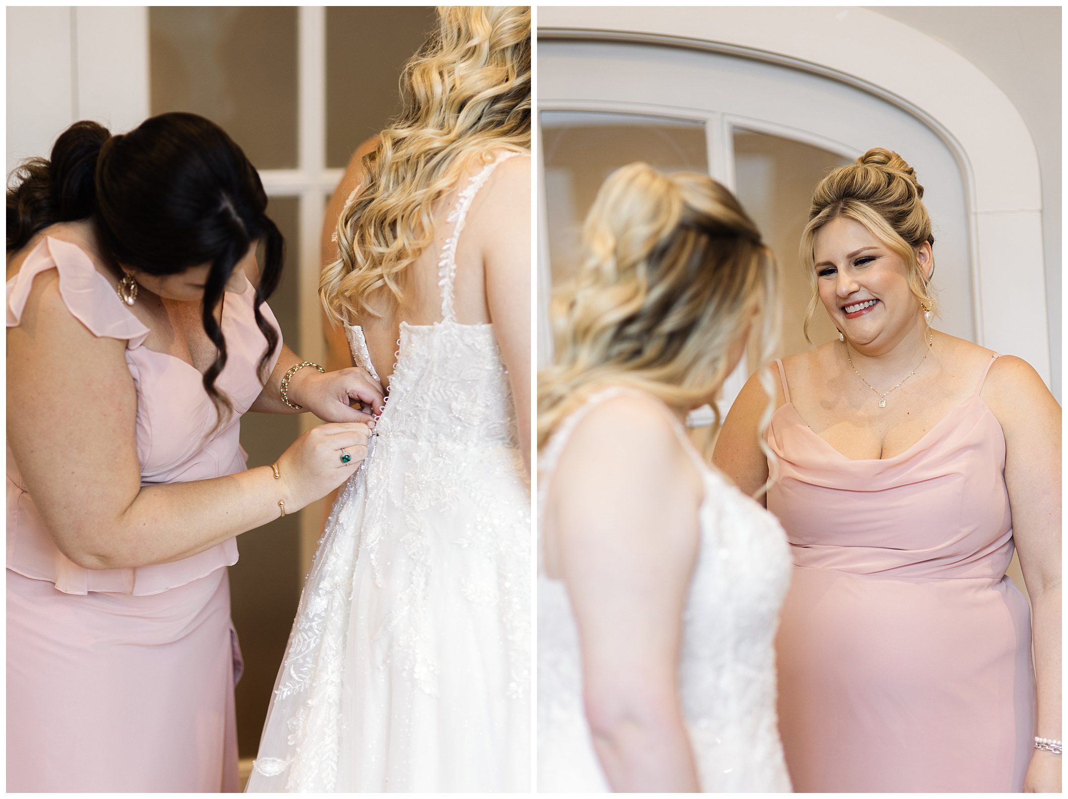 Two women in pink dresses help a smiling bride in a white gown get dressed for her mountain wedding, indoors in a brightly lit room with arched windows.