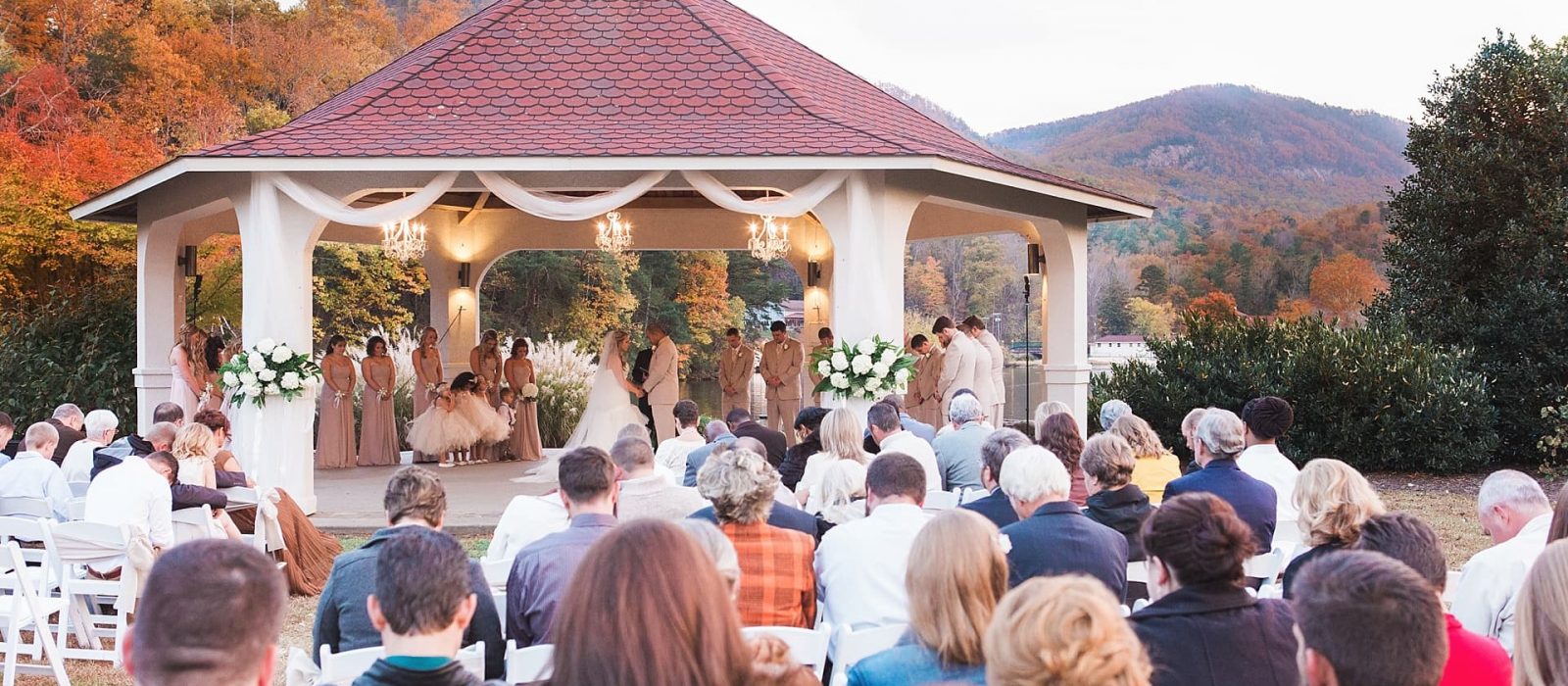 Outdoor wedding ceremony with lake and fall leaves in background by kathy beaver photography, Asheville NC