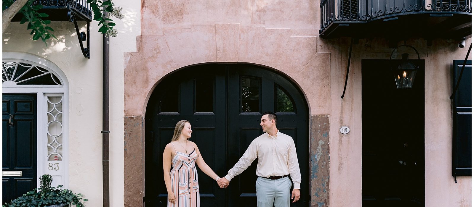 Couple standing in front of beautiful doors in Charleston, SC for their engagement portraits taken by Kathy Beaver Photography, a South Carolina wedding photographer.