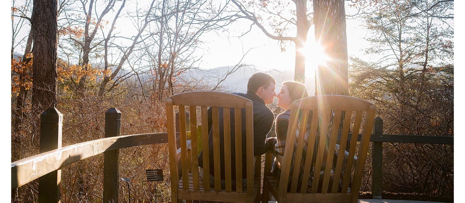 young engaged couple sitting on deck kissing at sunset