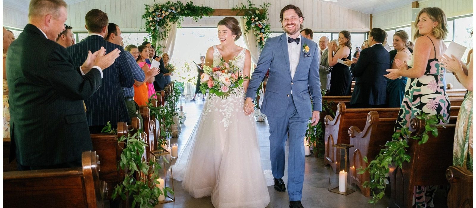 A bride and groom walking down the aisle of a church.