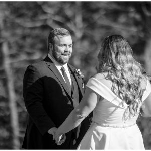 Black and white photo of a bride and groom in the woods.